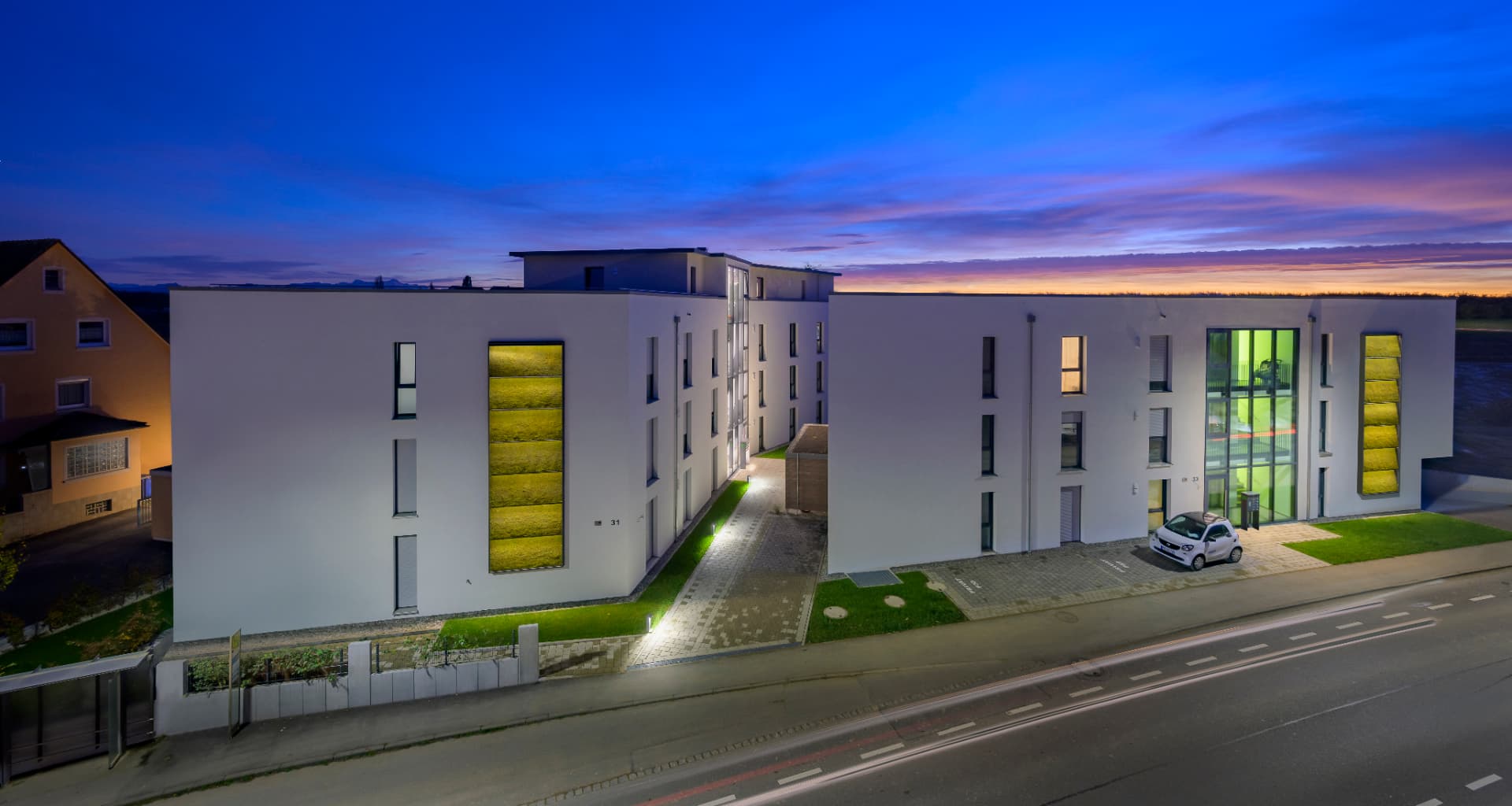Wohnprojekt Kluftern in der Abenddämmerung, Straßenansicht der beiden Mehrfamilienhäuser