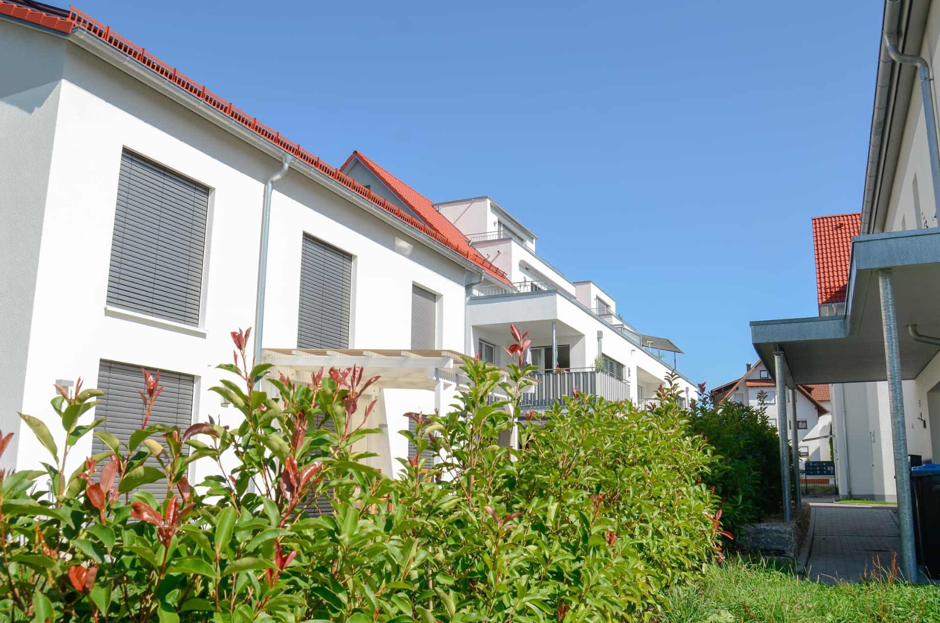 Straßenseitige Ansicht der Wohnhäuser mit Pergola und Bepflanzung